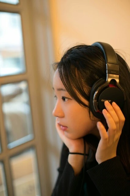 Daun Kim wearing headphones by a window